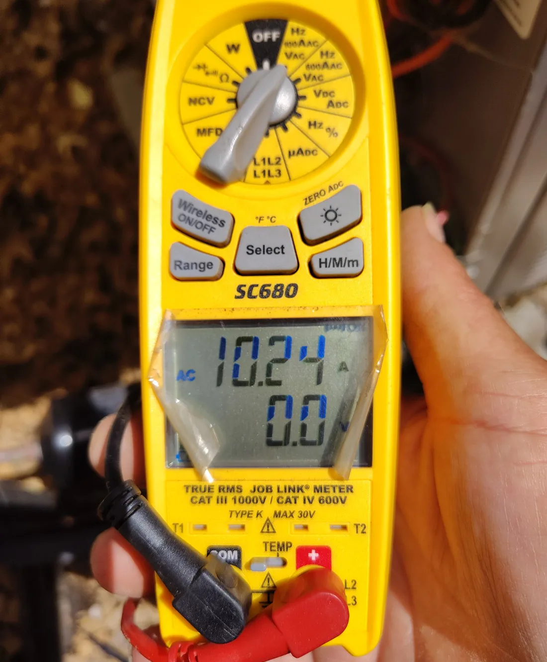 Digital clamp meter displaying an electrical measurement during outdoor AC testing