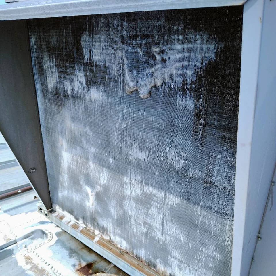 Outdoor rooftop HVAC coil covered in foaming cleaner during a cleaning process