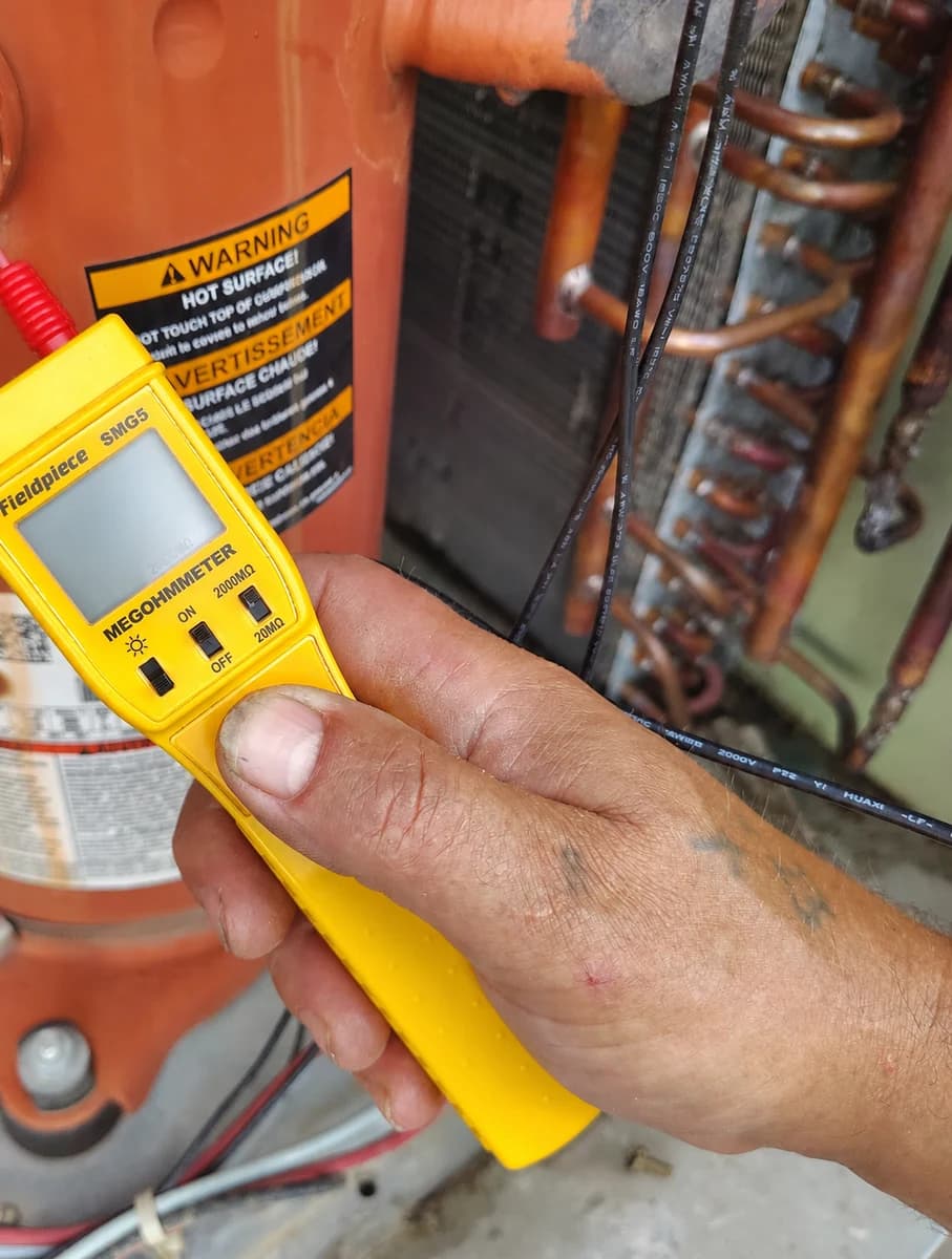 Technician meter leads checking compressor insulation resistance